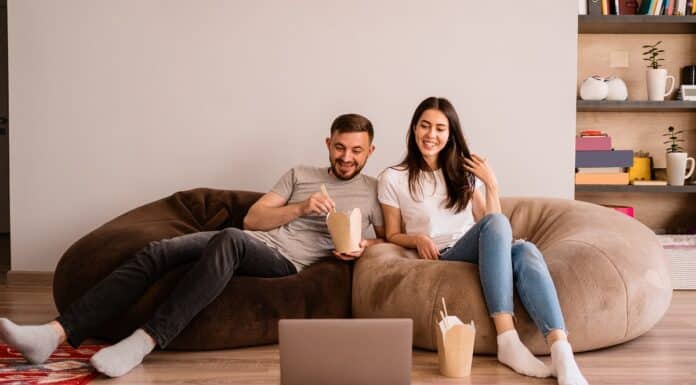 Happy couple enjoys time together while eating together and watching a movie on the laptop. How To Make A Bean Bag.