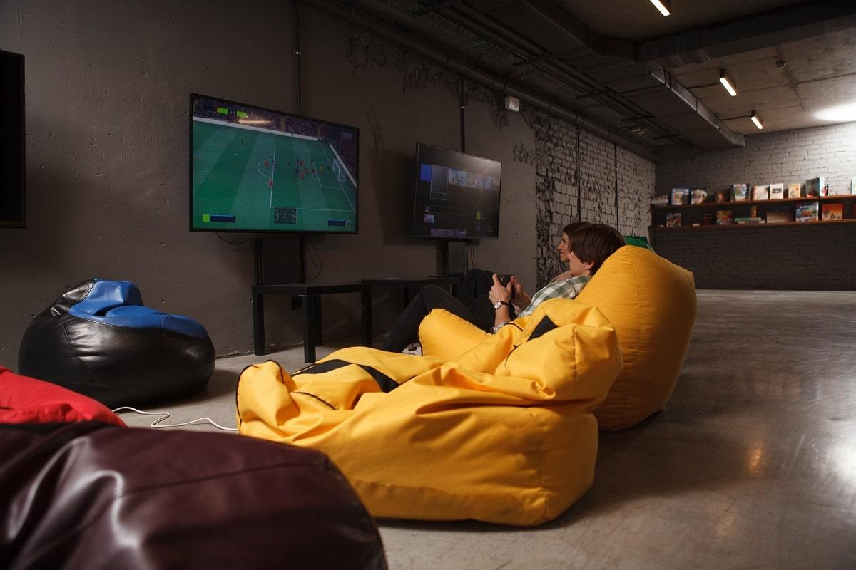 Rear view shot of two friends sitting in beanbag chairs enjoying playing video games. How to make a bean bag.