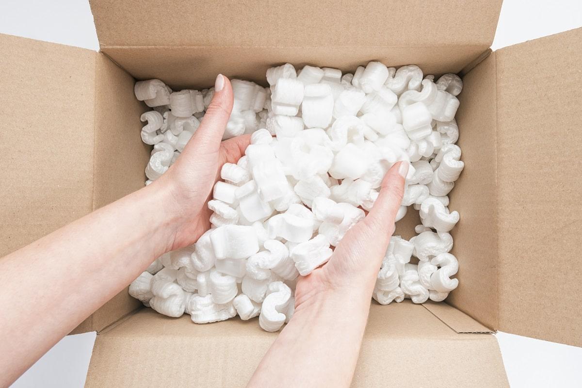 Female hands digging in a box with white packing peanuts. Ideal for websites and magazines layouts. The selection of bean bag fillings.