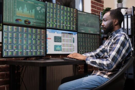 Brokerage company employee sitting at multi monitor workstation while trading risk free assets. Investment company trader using forex exchange platform and real time statistics to predict market trend. How to configure multiple monitors to your computer.
