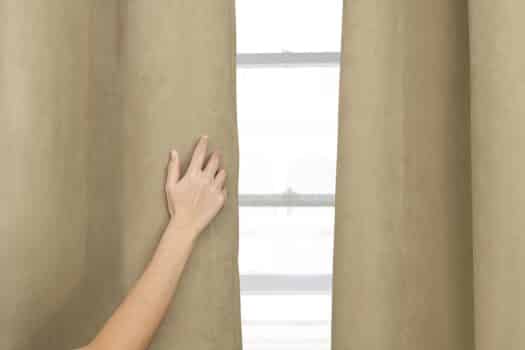 Beige curtain home decor, with female hand. How to get creases out of blackout curtains.