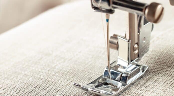 Modern sewing machine presser foot with linen fabric and thread, closeup, copy space. Sewing process clothes, curtains, upholstery. Business, hobby, handmade, zero waste, recycling, repair concept. How To Make Blackout Curtains.