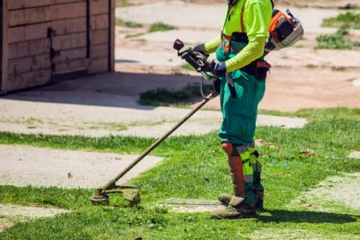 Road landscapers in uniform cutting grass in the park using string lawn trimmers. 2-cycle weed eater or 4-cycle weed eater– how to choose the right one for your lawn.