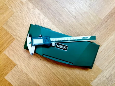 Digital caliper sitting on case on wooden floor