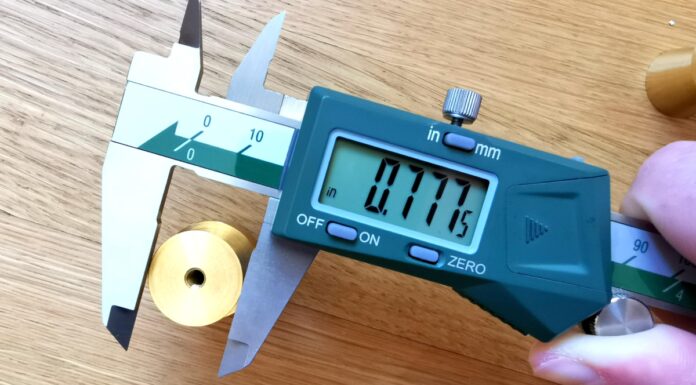 digital calipers measuring a piece of brass hardware