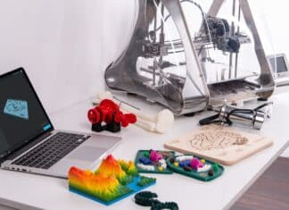 a couple of colored 3d printers near laptop and 3D printer