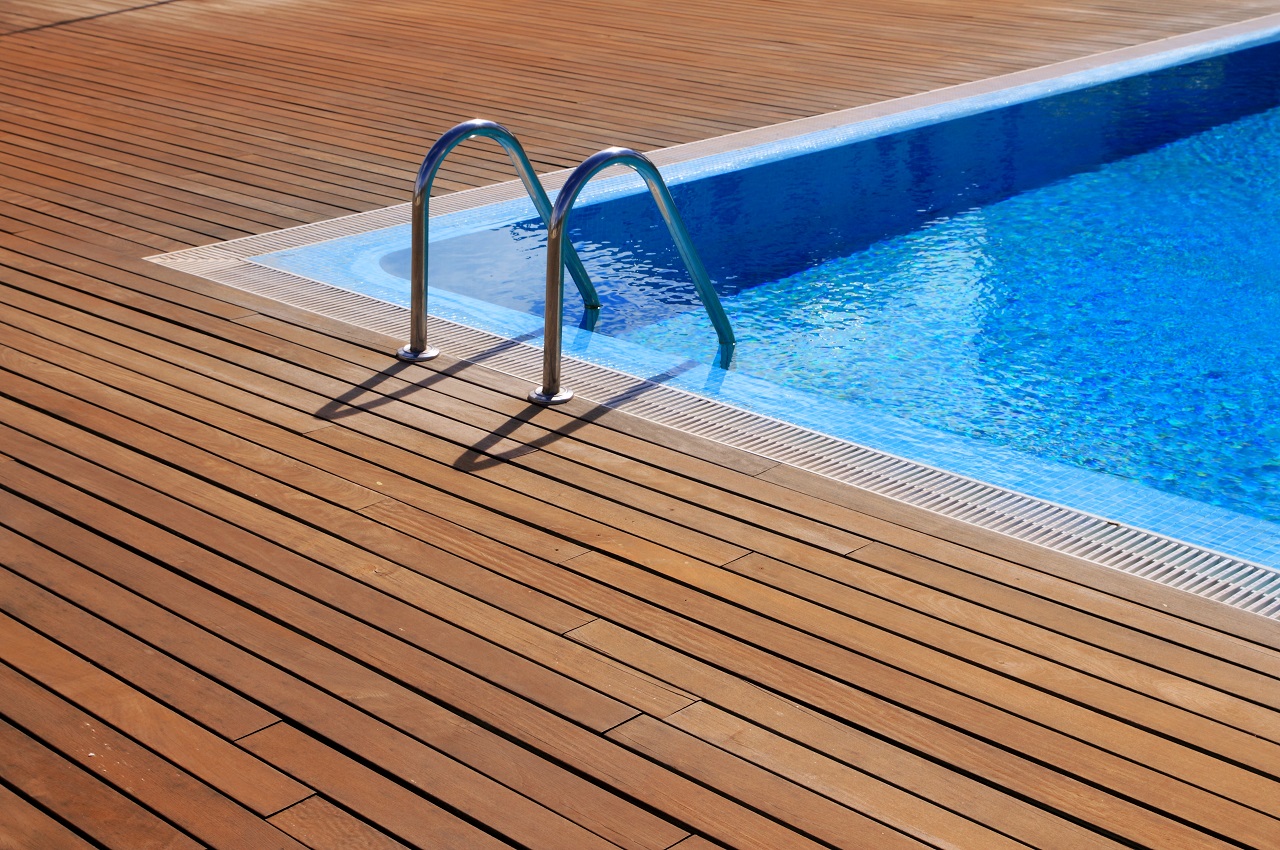Blue swimming pool with teak wood flooring ،es summer vacation. Swimming pool with wooden decking.