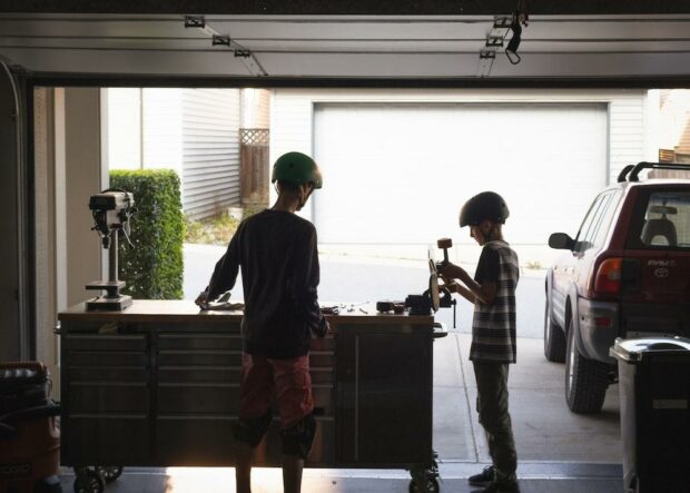 Two boys working on a skateboard in the garage