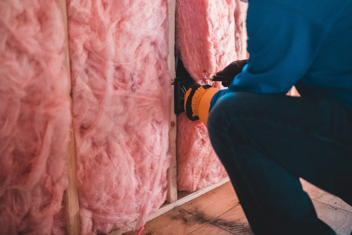 Worker adding soundproofing insulation between studs