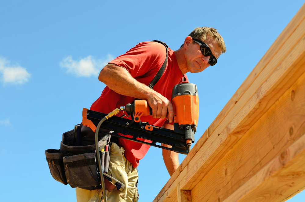 A carpenter with a framing nailer gun