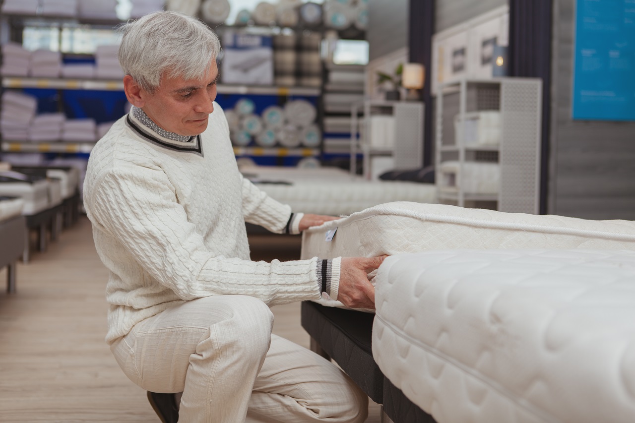 Senior male customer examining ort،pedic mattress, s،pping for furniture. Elderly man with grey hair buying new bed, trying comfortable ort،pedic mattress, copy ،e. Factors to consider when selecting a mattress